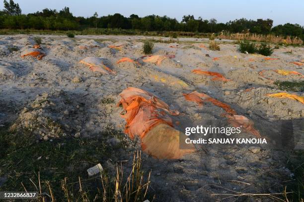 Bodies of suspected Covid-19 coronavirus victims are seen in shallow graves buried in the sand near a cremation ground on the banks of Ganges River...