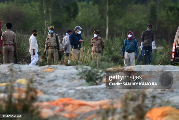 Police and administrative officials inspect a cremation ground on the banks of Ganges River, where suspected bodies of Covid-19 coronavirus victims...