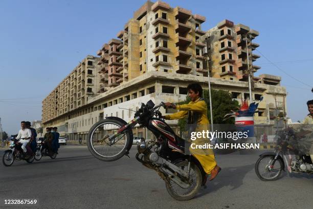 Man performs a stunt with a motoebike some stunts on his bike near the closed Clifton beach on the first day of Eid al-Fitr, which marks the end of...