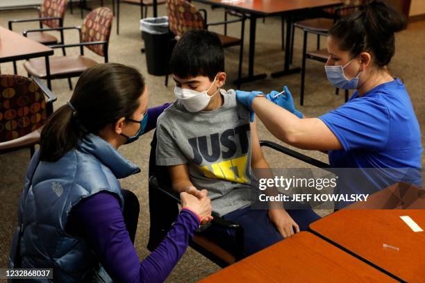 Jamie Blank holds her son, Ari Blank's hand as he receives the Pfizer-BioNTech Covid-19 vaccine from healthcare worker Jen Feinberg at the Jewish...