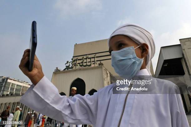 Bangladeshi Muslim boy takes a selfie as he and Muslims gather to offer Eid-Al-Fitr prayer at the Baitul Mukarram National Mosque after end of the...