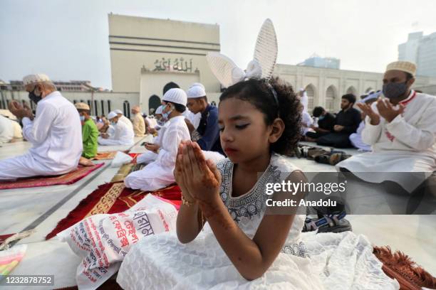 Bangladeshi girl prays as she and Bangladeshi Muslims gather to celebrate Eid-Al-Fitr festival during a lockdown following the COVID-19 coronavirus...