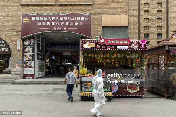 Health worker wearing personal protective equipment walks past stalls at the Xinjiang International Grand Bazaar in Urumqi, Xinjiang province, China,...