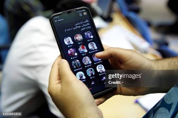 Picture taken in the Iranian capital Tehran on May 14, 2021 shows an Iranian man checking the Clubhouse App on his smart phone. - As Iran gears up...