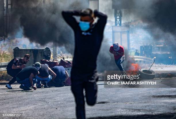 Palestinians run as others take cover, during confrontations with Israeli security forces near the Hawara checkpoint south of the occupied West Bank...