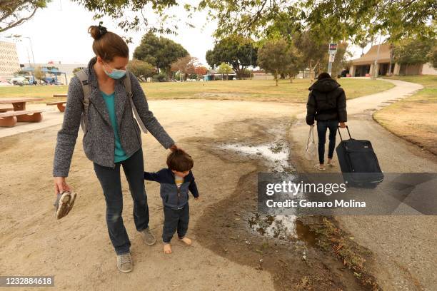 Stephanie Popescu and her son Dacian, 2 1/2 years old, head to the playground for a playdate with other children as a homeless woman walks by with...