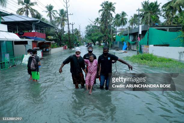 Police and rescue personnel evacuate a local resident through a flooded street in a coastal area after heavy rains under the influence of cyclone...