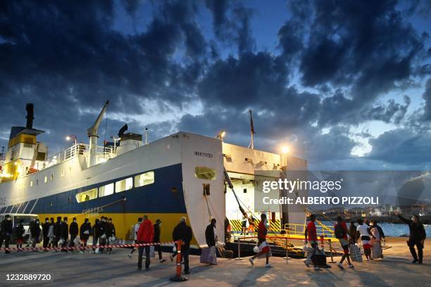 Migrants from a migrant housing centre on the Italian island of Lampedusa, are guided by a security official on May 14 as they prepare to board the...
