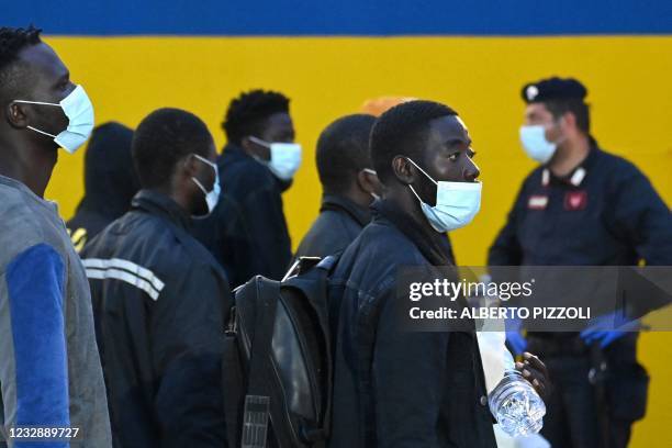 Migrants from a migrant housing centre on the Italian island of Lampedusa, are watched by a security official on May 14 as they prepare to board the...