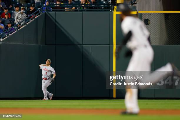 Left fielder Shogo Akiyama of the Cincinnati Reds throws the ball to the infield as Charlie Blackmon of the Colorado Rockies runs to third base on a...