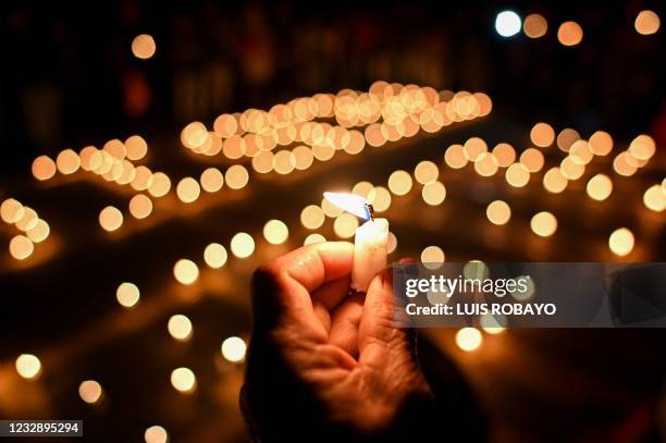 Person holds a holds a burning candle during a vigil for a girl who was assaulted by police officers during protests and later committed suicide, in...