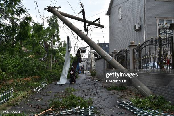 People pass under a damaged utility pole after a tornado hit the city of Suzhou in China's eastern Jiangsu province province on May 15, 2021. - China...