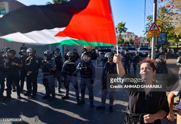 Woman raises a Palestinian flag in front of Israeli security forces standing guard, during a protest in the coastal city of Jaffa, near Tel Aviv, on...