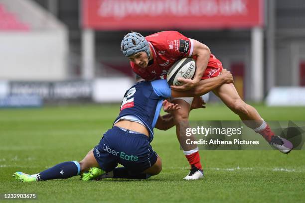 Jonathan Davies of Scarlets is tackled by Ben Thomas of Cardiff Blues during the Guinness Rainbow Cup match between the Scarlets and Cardiff Blues at...