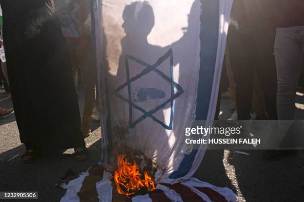 Supporters of Iraqi Shiite cleric Muqtada al-Sadr burn a makeshift Israeli flag during a march in solidarity with the Palestinians, in the southern...