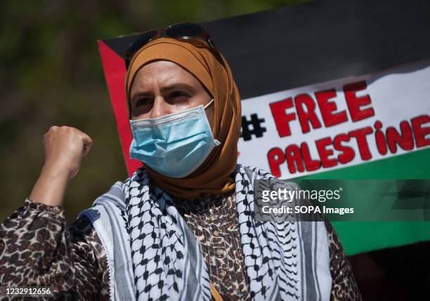 Woman wearing a face mask is seen rising her fist as she takes part during a protest against israeli apartheid and armed attack to Gaza on...