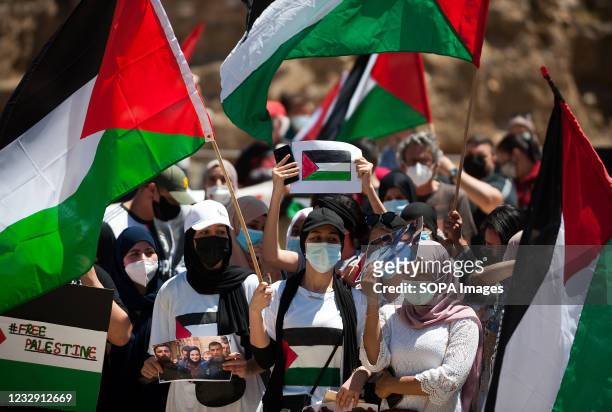 Protesters wearing face masks are seen holding placards and flags as they take part during a protest against israeli apartheid and armed attack to...
