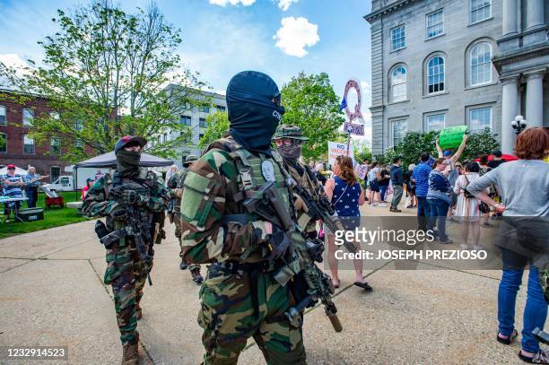 Armed members of the New England Minutemen militia group walk among rally goers during the anti-mask and anti-vaccine "World Wide Rally for Freedom"...