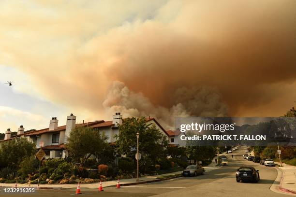 Helicopter is seen flying above the plume of smoke created by the Palisades fire in Topanga State Park, North West of Los Angeles on May 15, 2021. -...