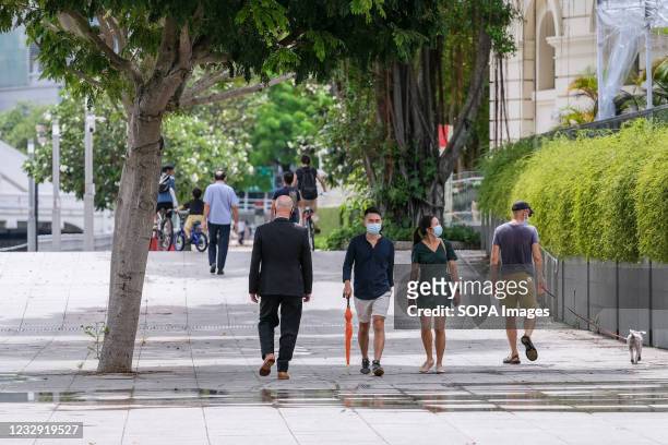 People wearing face masks as a preventive measure against the spread of covid19 walk along the Singapore River. Singapore will be tightening its...