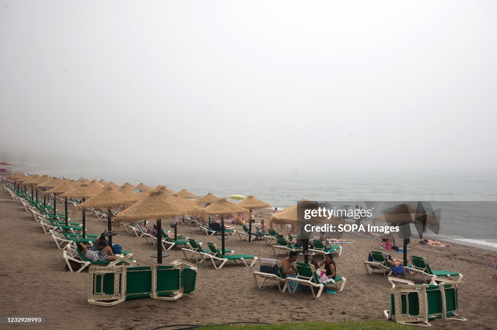 Bathers are seen sitting under the beach umbrellas at...