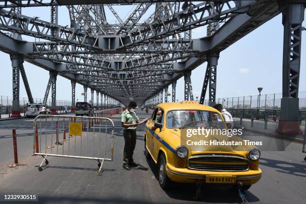 Police personnel checking commuters in a yellow taxi during a Covid-19 induced lockdown imposed from today morning to May 30, at the Howrah Bridge on...