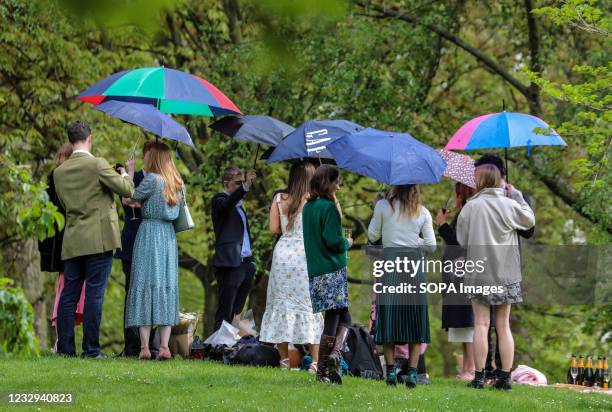 Group of people holds umbrellas to protect themselves from the rain at an outside social gathering in London's St James's Park over the weekend.