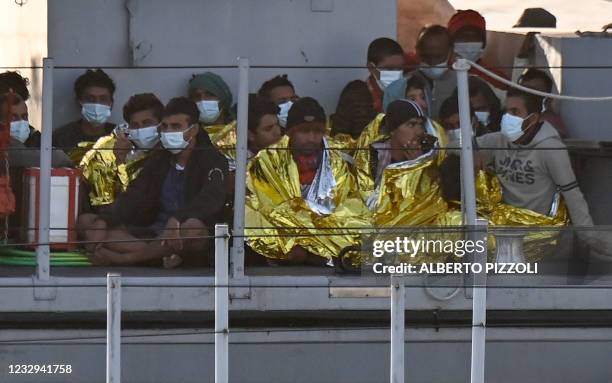 Migrants warmed by emergency blankets arrive on a boat of the Italian Guardia Di Finanza law enforcement agency on May 17, 2021 to disembark on the...