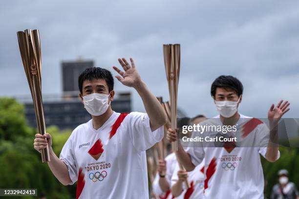 Tokyo 2020 Olympic torch bearers wave during the torch relay in the Hiroshima Peace Park on May 17, 2021 in Hiroshima, Japan.