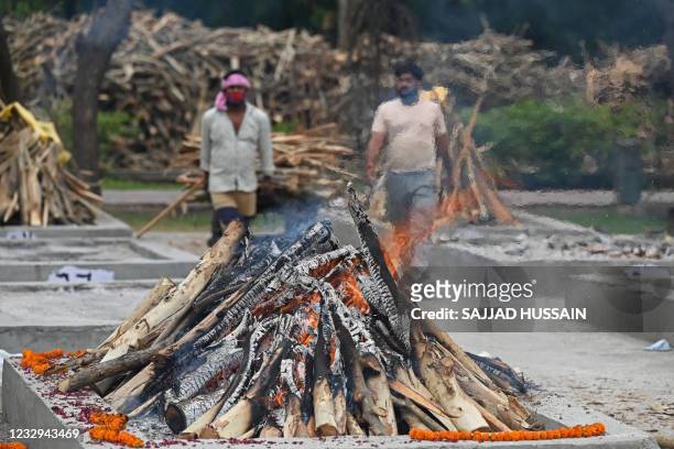 Workers walk amid the burning funeral pyres of people who died due to the Covid-19 coronavirus at a cremation ground in New Delhi on May 17, 2021.