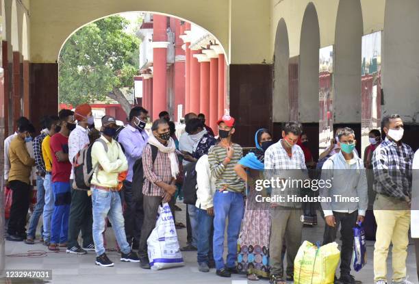 Migrants stand in a queue for Covid-19 tests before boarding trains to their homes during a Covid-19 lockdown, at the city railway station, on May...