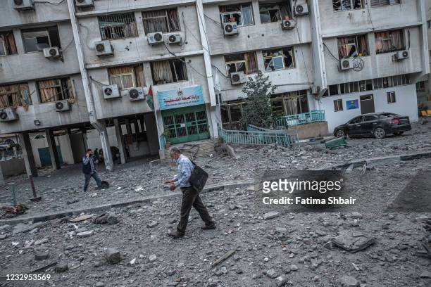 People inspect the rubble following an Israeli airstrike on the upper floors of a commercial building near the Health Ministry in Gaza City on May...