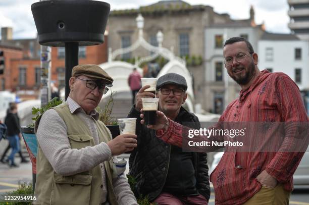 Locals enjoy a take away pint of Guinness in a plastic cups near Ha'Penny Bridge in Dublin city center. Ireland takes another step towards normality...