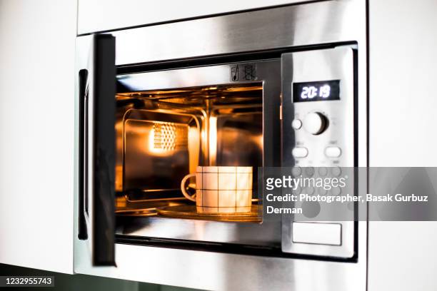 reheating / cooking a cup of drink in the microwave oven - microwave oven stockfoto's en -beelden