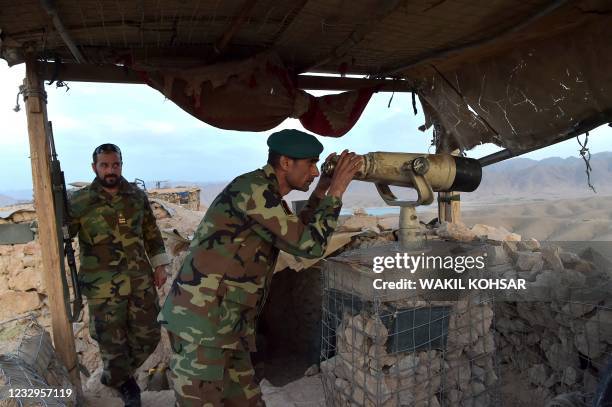 In this photograph taken on March 23 Afghan National Army commander Dost Nazar Andarabi keeps watch with binoculars at an outpost set up against...