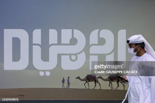Visitor walks past a Dubai billboard at the Arabian Travel market exibition in the Gulf emirate, on May 17, 2021. - Egypt is prioritising the...