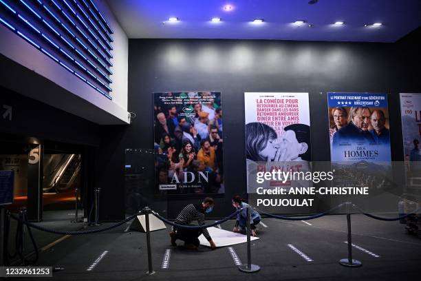 Members of staff prepare movie posters in order to display them at the entrance of the cinema complex of the UGC Cine Cite Les Halles, in Paris, on...