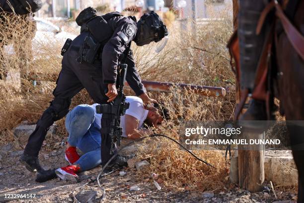 Israeli border police detain a Palestinian man during protests against Israel's occupation and its air campaign on the Gaza strip, at the flashpoint...