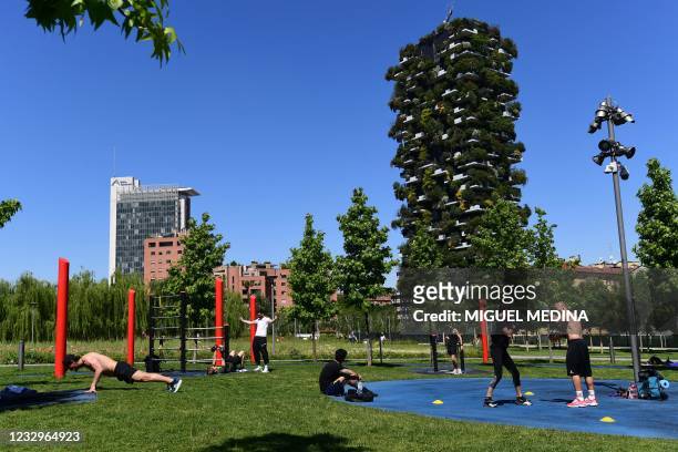 People exercise in the botanic park "Library of Trees" with in background the Vertical Forest high-rise complex in the modern district of Porta Nuova...