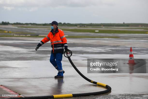 Ground crew worker holds a fuel nozzle as an Airbus A350 passenger plane, operated by Air France-KLM, fills up with sustainable aviation fuel on the...