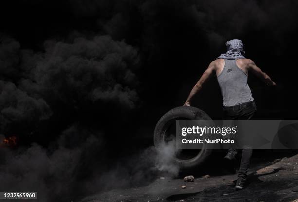 Palestinian protester carries tyres to set them ablaze during clashes near the Jewish settlement of Beit El near Ramallah, West Bank, on May 17, 2021...