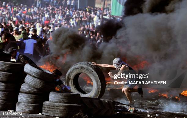 Palestinian protesters confront Israeli troops at the Hawara checkpoint south of Nablus city in the occupied West Bank on May 18 during a...