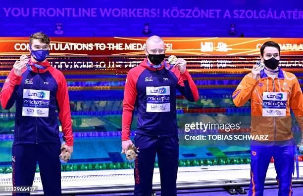 Great Britain's Adam Peaty poses with his gold medal past silver medallist Netherlands' Arno Kamminga and bronze medallist Great Britain's James...