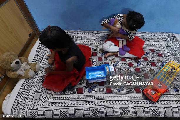 In this picture taken on May 11 twin sisters Tripti and Pari, who lost both their parents due to the Covid-19 coronavirus, play with their toys at a...