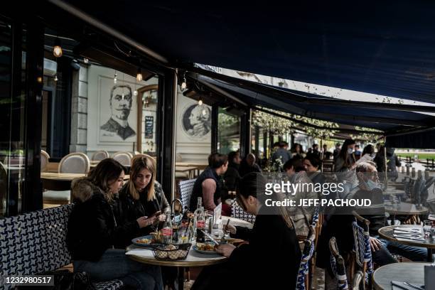 Customers eat while sitting on the terrace of a restaurant in Lyon on May 19 as cafes, restaurants and other businesses re-opened after closures...