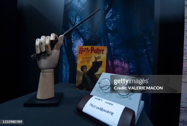 Harry Potter's wand and eyeglasses are exhibited by a copy of "Harry Potter and the Deathly Hallows" during a press preview of Prop Store's Iconic...