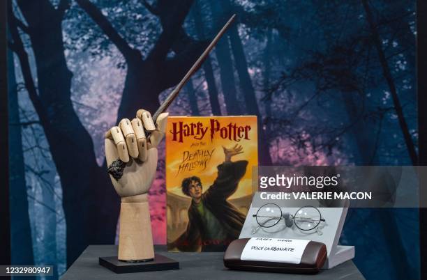Harry Potter's wand and eyeglasses are exhibited by a copy of "Harry Potter and the Deathly Hallows" during a press preview of Prop Store's Iconic...