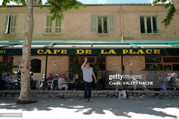 An enthusiast plays "petanque" in the shadow of a tree in front of a restaurant terrace at Saint-Paul-de-Vence, southern France on May 19 as cafes,...