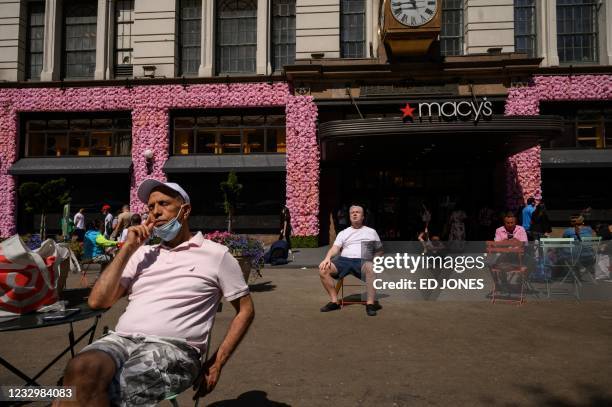 People sitting in chairs enjoy sunbathing in a public square outside the Macy's department store in central Manhattan, New York city on May 19, 2021....