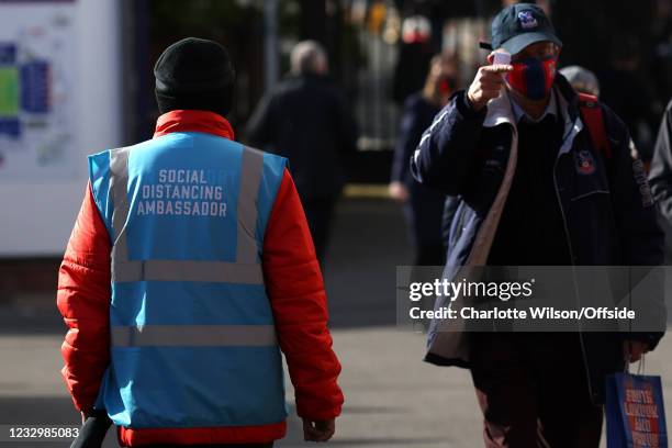 Steward wearing a vest with the title of Social Distancing Ambassador walks past fans ahead of the Premier League match between Crystal Palace and...